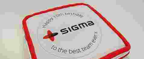A white cake with an iced red border with the Sigma logo on it and words reading, "Happy 10th birthday to the best team ever x"