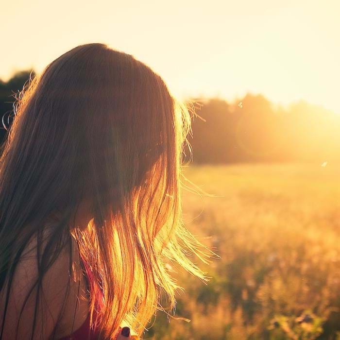 Photograph of a young lady in a field at sunset