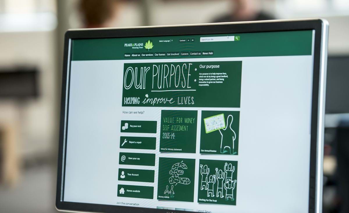 A photo of the Peaks and Plains website homepage shown on a monitor