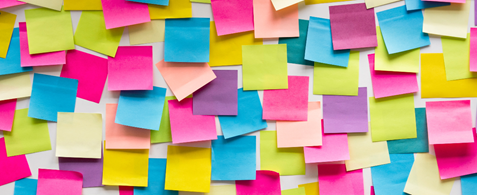 A wall covered in blank multi coloured post it notes