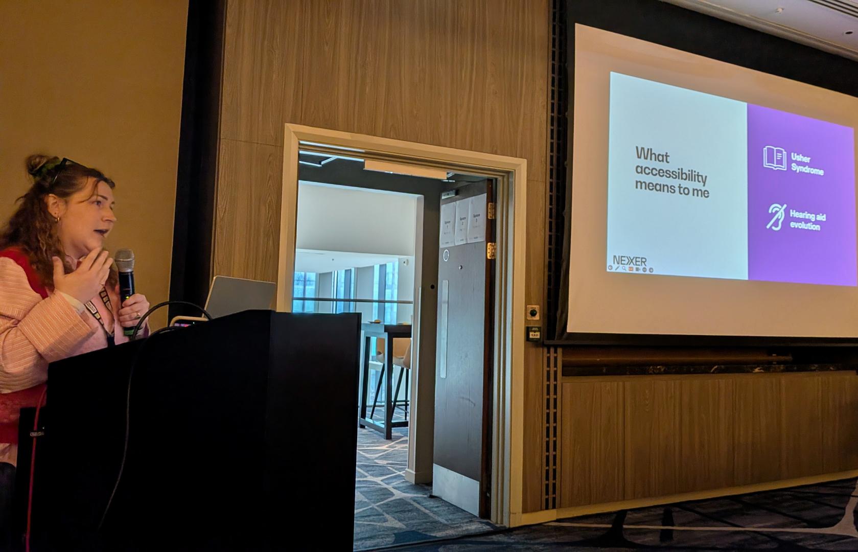A speaker stands next to a slide reading 'What accessibility means to me'