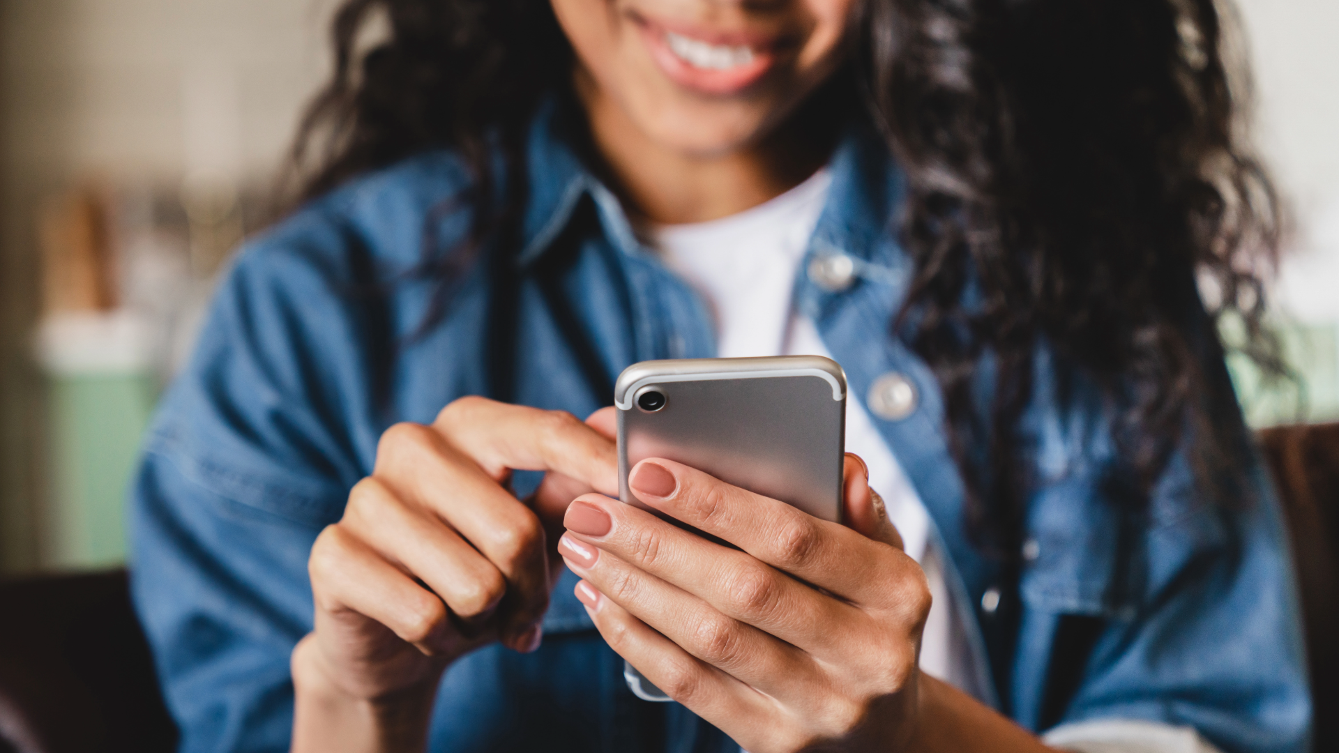 A person typing on a smartphone and smiling 