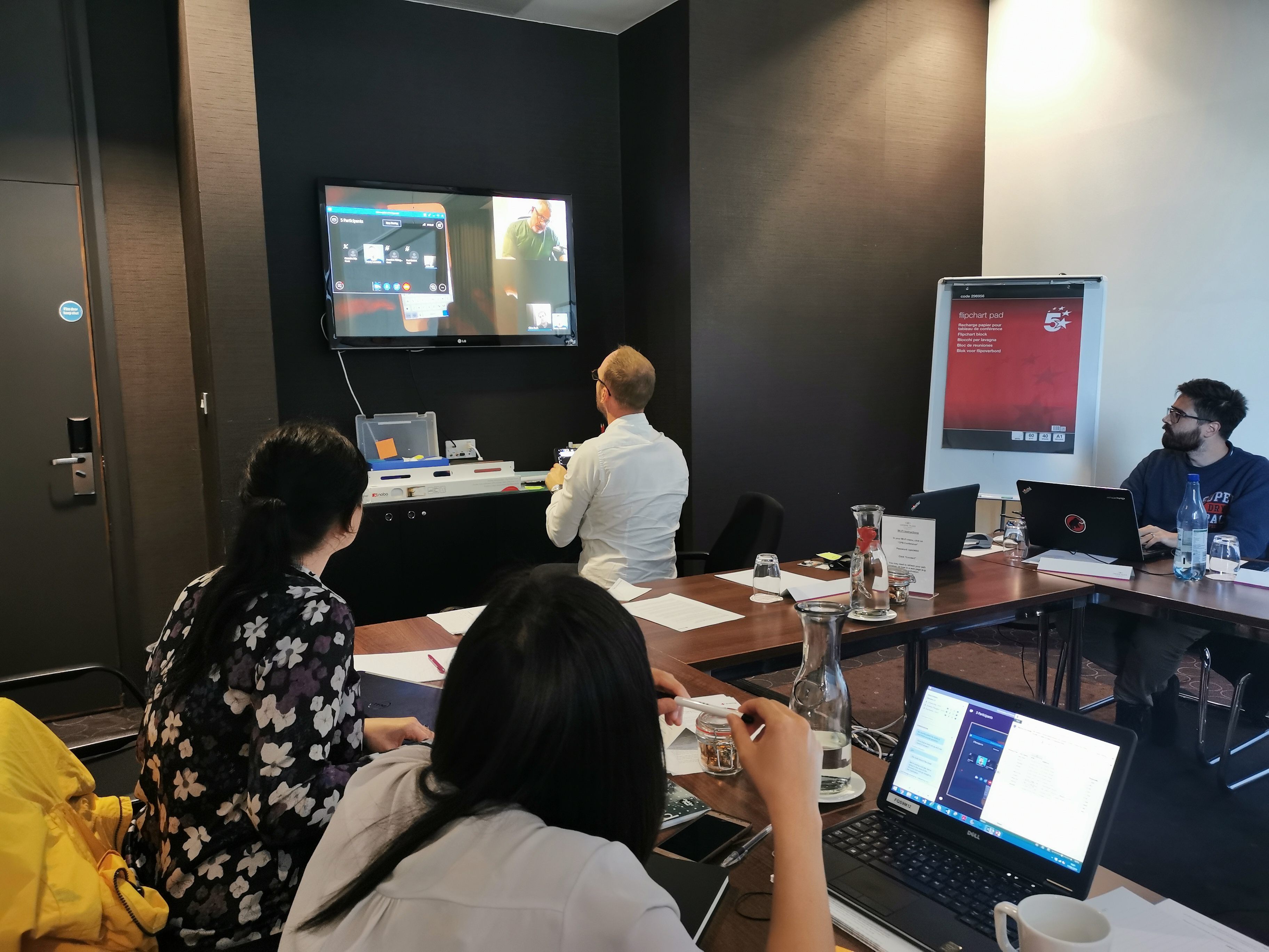 People sat around a table looking at a TV on the wall observing user testing.