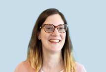 Photo of Lou Shackleton, a smiling white woman with dark hair and glasses.