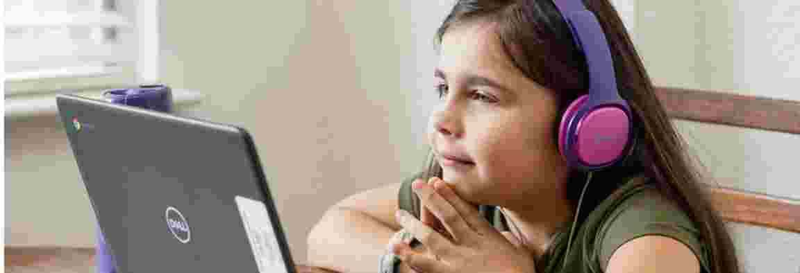 Child looking at a laptop screen, wearing pink headphones and smiling