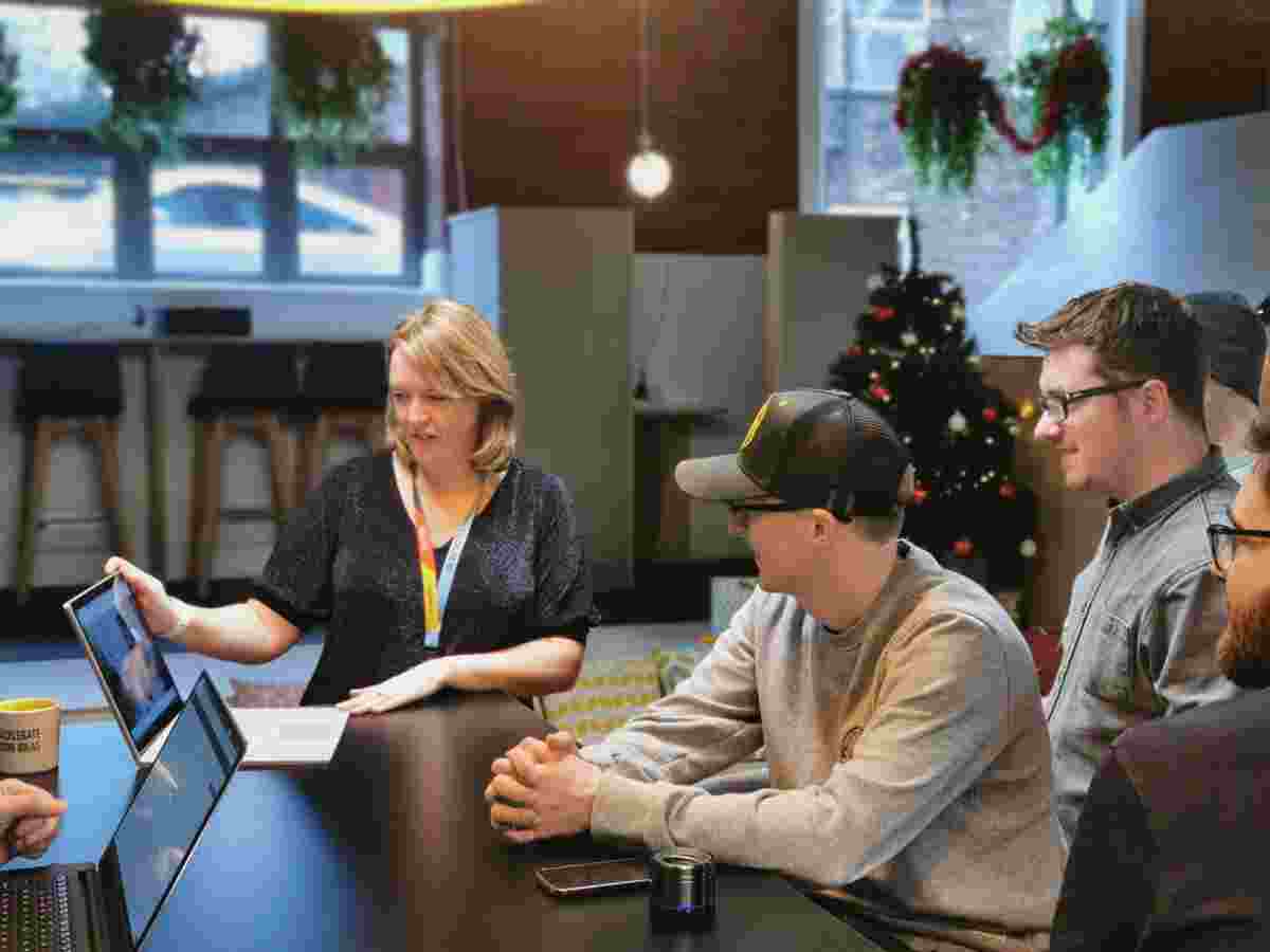 Three people stood around a laptop 