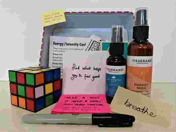 A mental health first aid kit with a rubix cube, energy mists, intensity cards and post-it notes. 