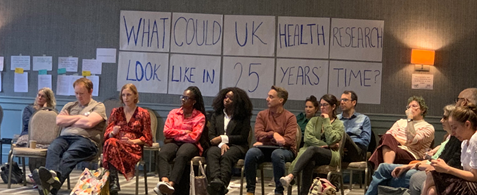 A group of people seated under a sign reading "What could UK health research look like in 25 years time' 