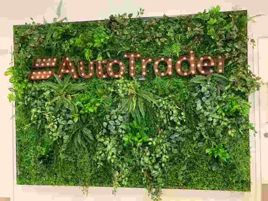 Metallic brown signage reading Auto Trader on a green leafy background