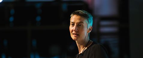 Janet Hughes. A thin white woman with short grey air, gesticulating to the left and looking inquistive.