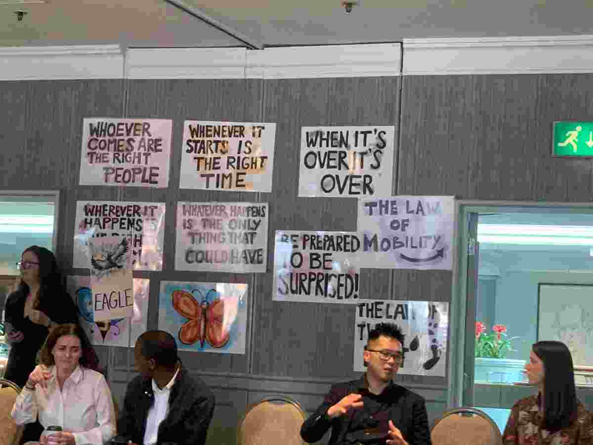 Seated people in discussion, with posters behind them featuring different ideas around health research