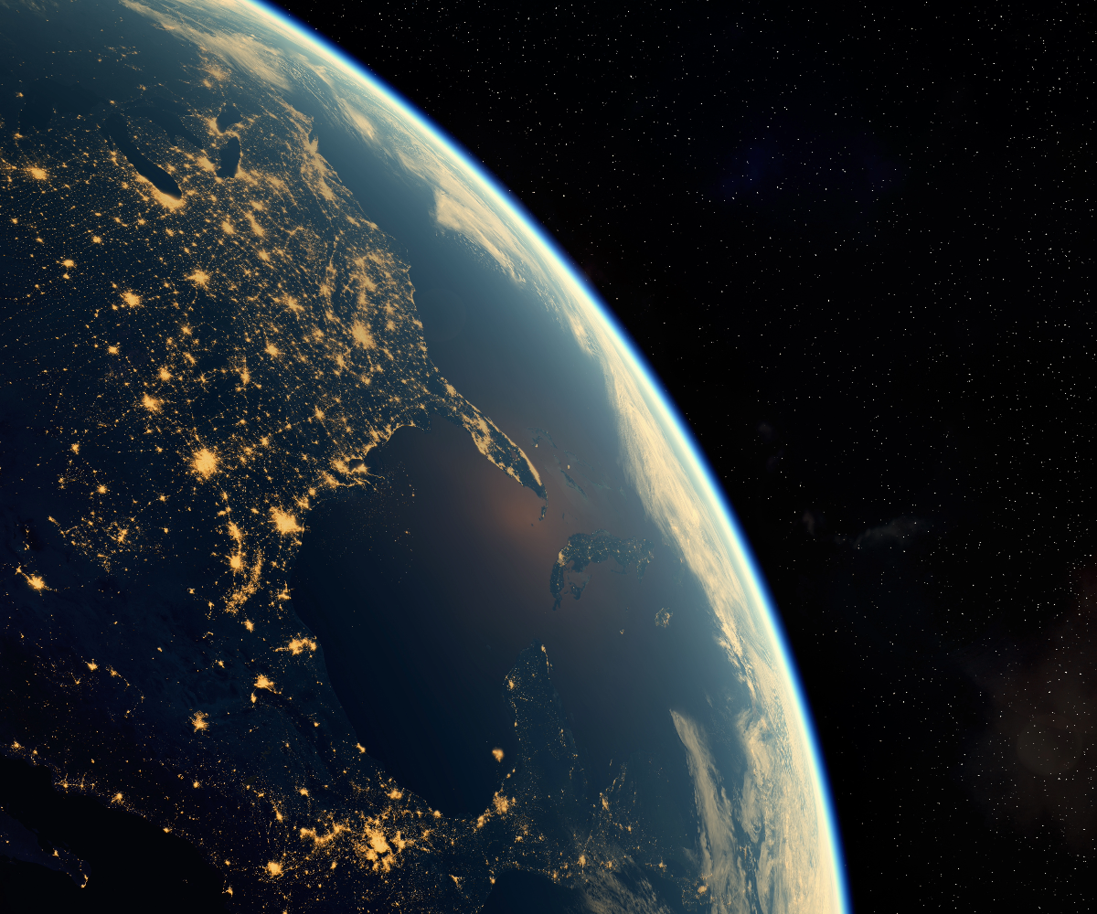A view from space of the earth lit up at night, with a network of connected lights visible between towns and cities.