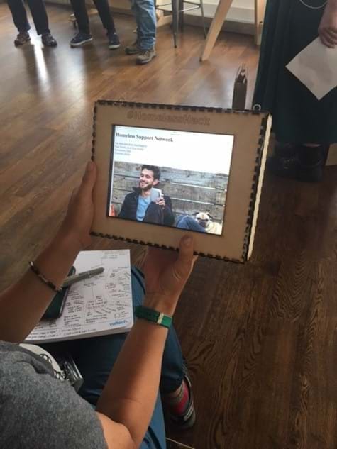 A white woman holding a tablet, with a prototype of a homeless hack solution.