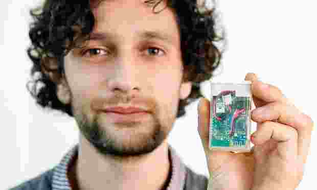 Tim Omer holding up part of the diabetes monitoring kit he built himself, which looks like a small Tic Tac box.