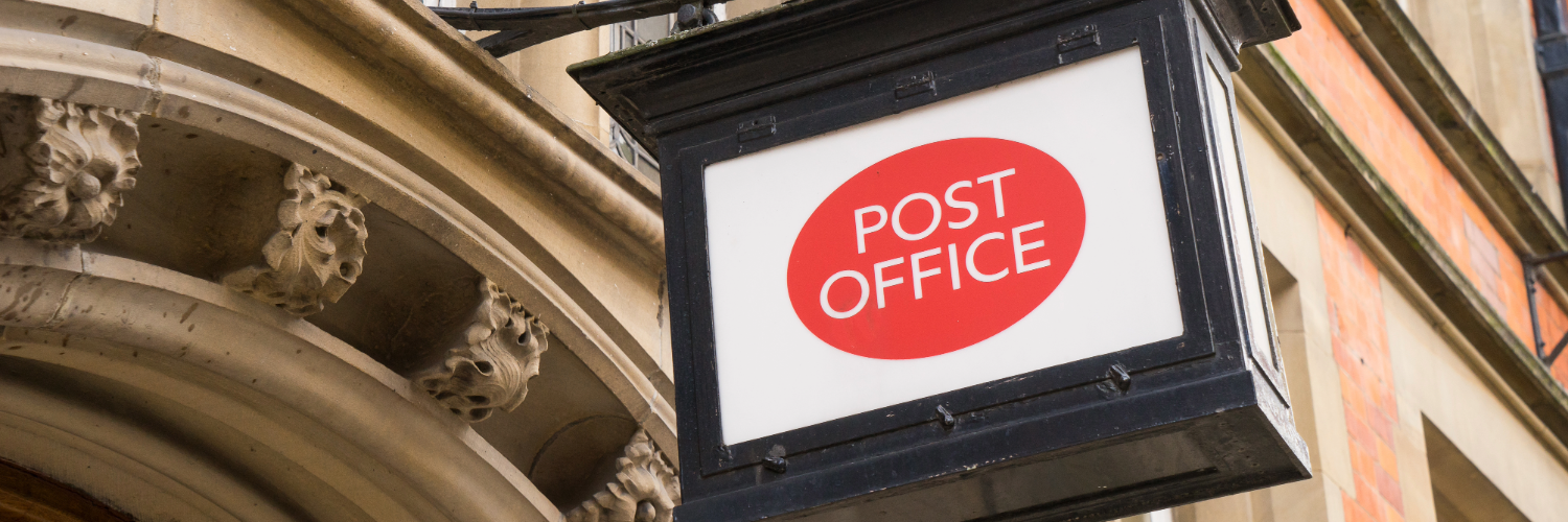 A post office logo on a sign outside a stone building
