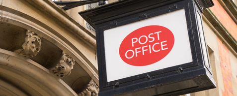 A post office logo on a sign outside a stone building