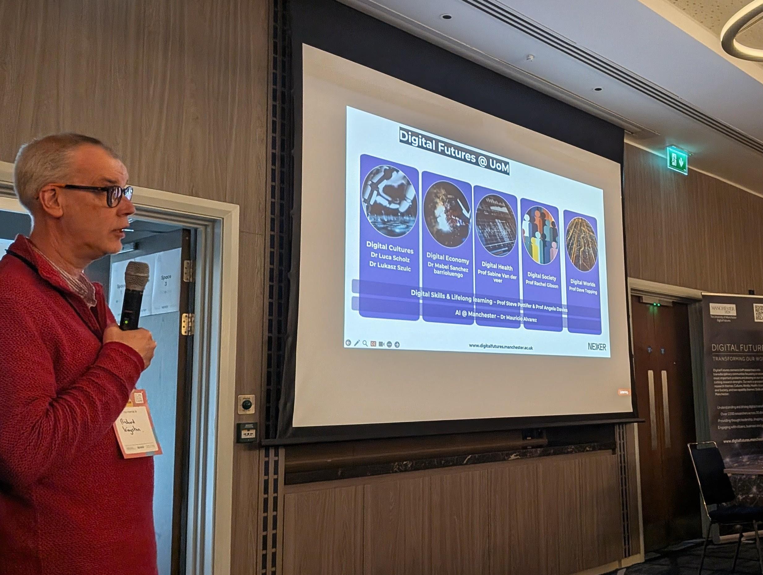 A speaker stands next to a slide reading 'Digital Futures at UoM'.