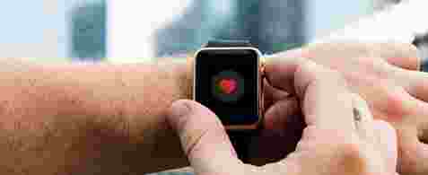 Arm with an apple watch on with a red heart displaying on the watch. 