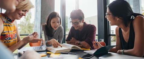University students sitting round a table with books open in front of them