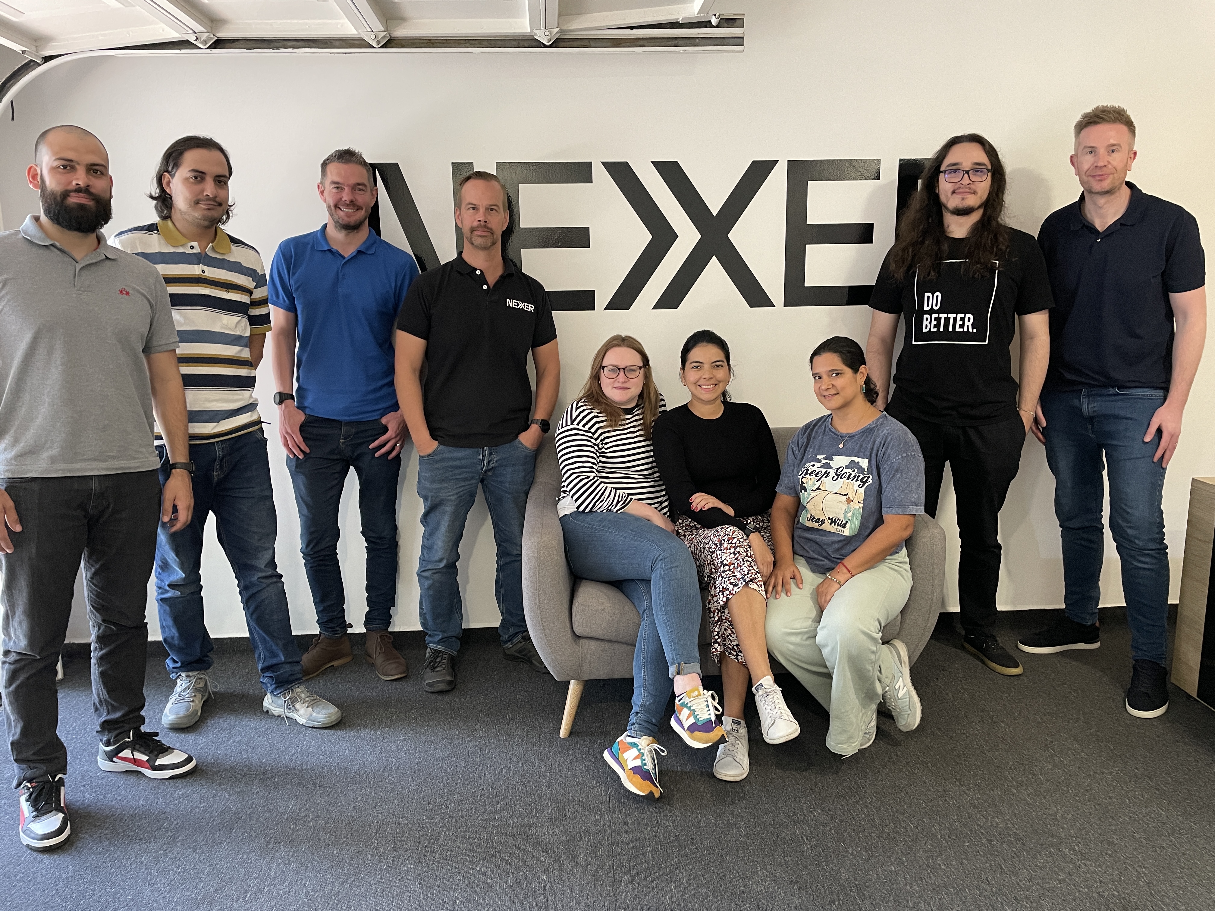 Members of Nexer's UK, India and Colombia teams gathered in a Nexer office, illustrating the global collaboration that supports 24/7 DevOps, digital transformation and accessibility services.