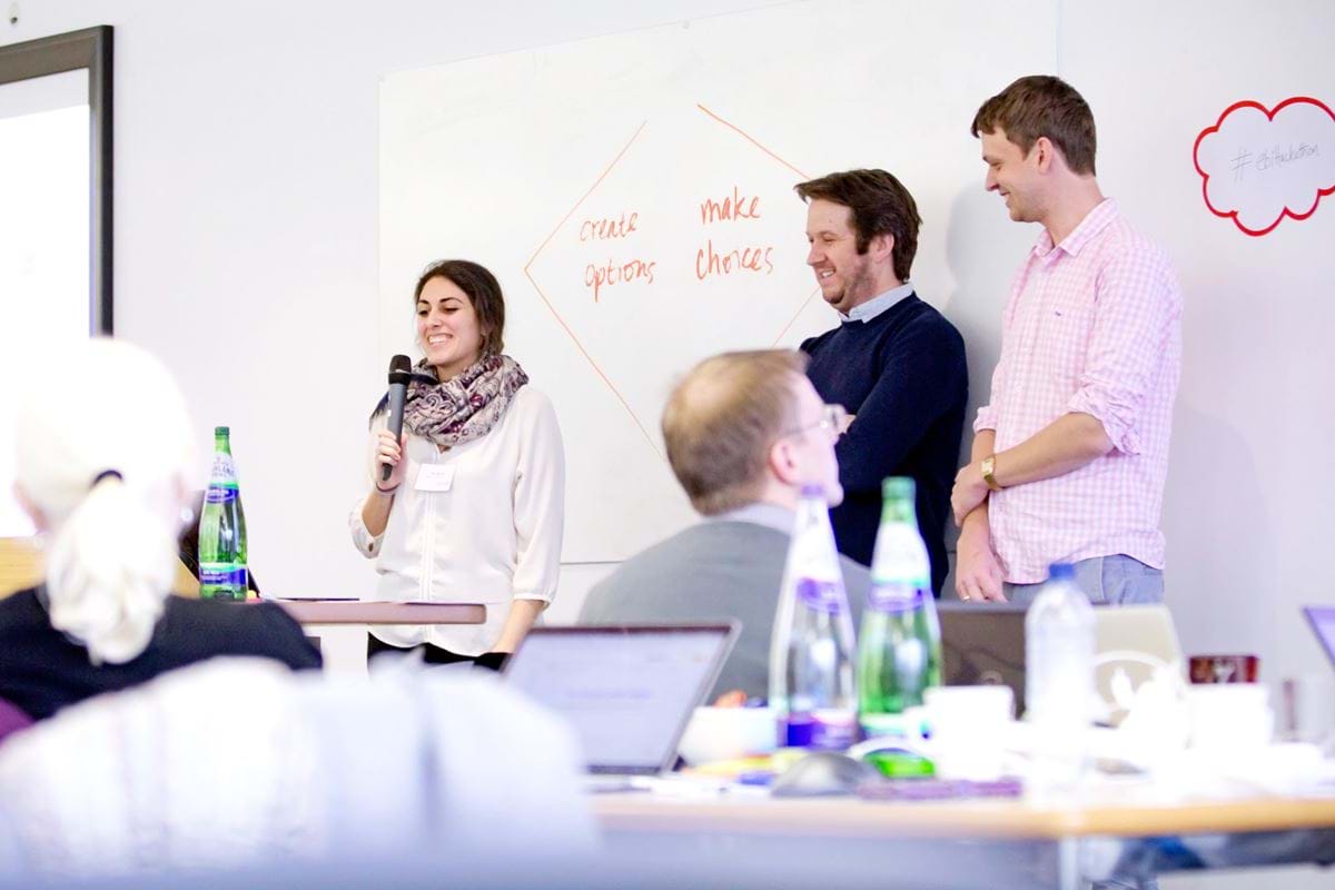 A group of white people stood in front of a whiteboard with the words, "create options, make choices" written on it.