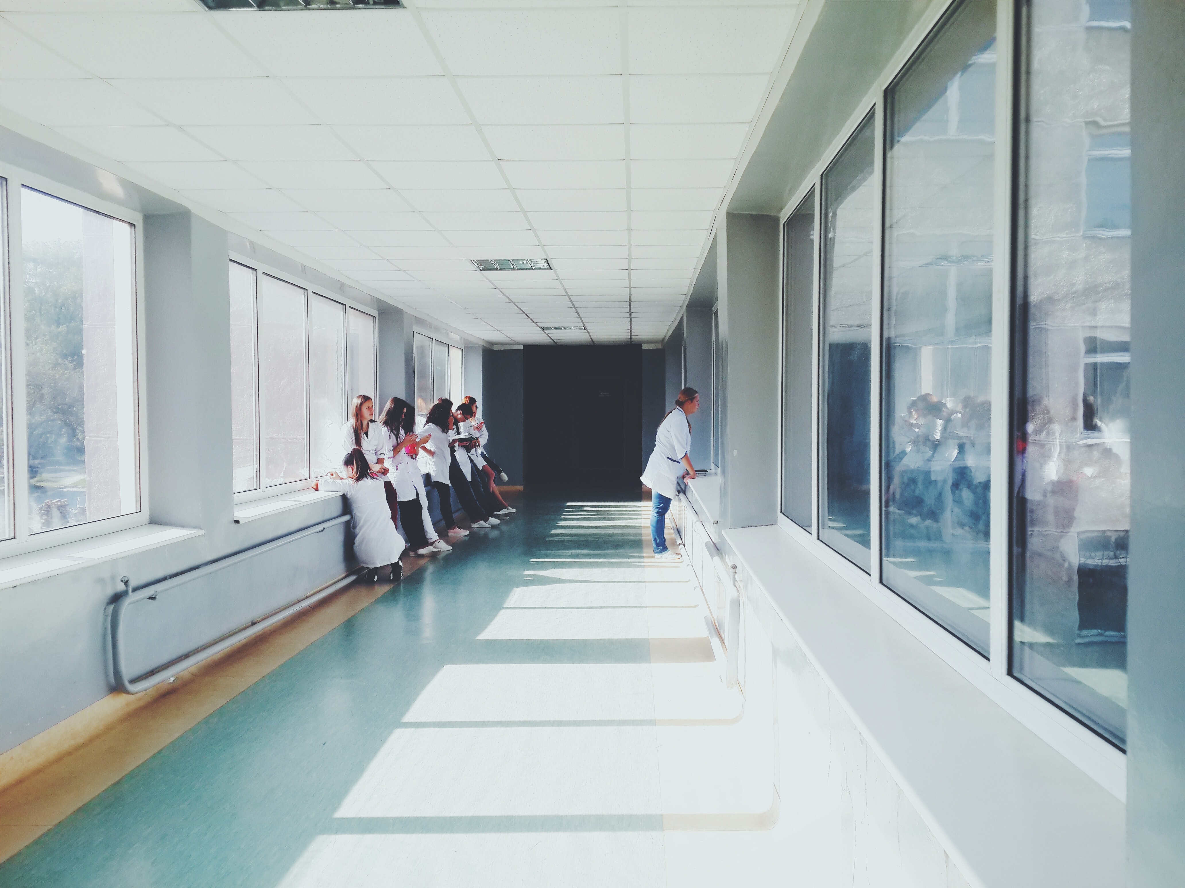 A long hallway with windows on both sides and Doctors And Patients stood against the side