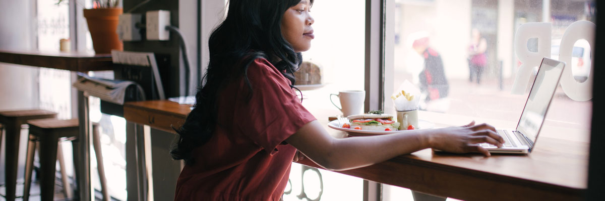 Woman in red dress using laptop on table